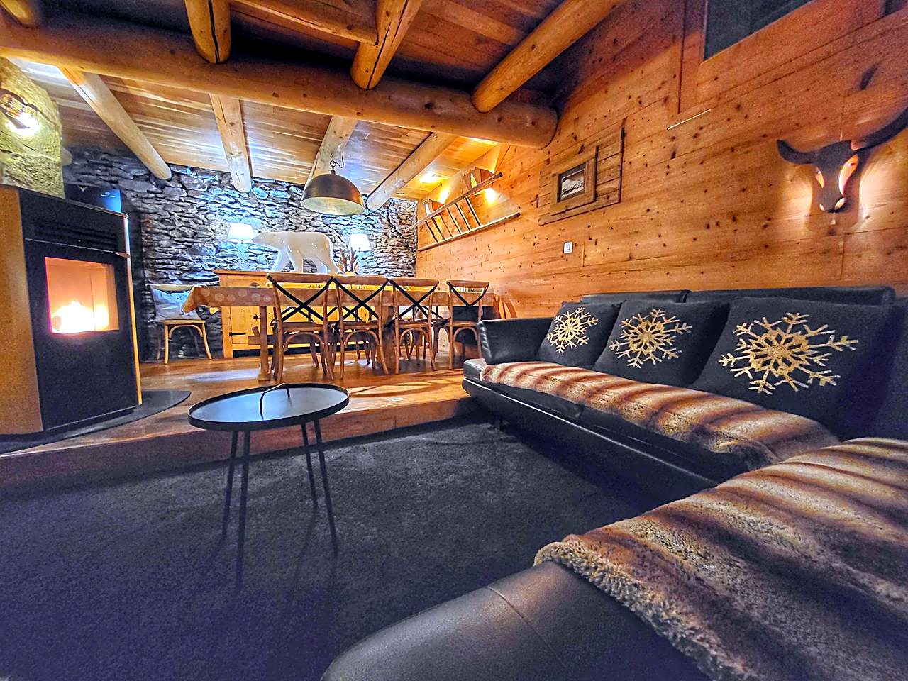 Grand salon du Cosy Lodge avec poêle à granulés et mur en pierre